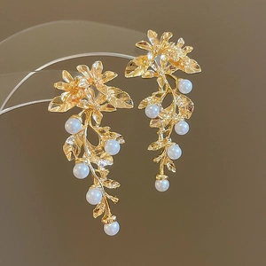 Détail de boucles d'oreilles vintage dorées avec perles blanches et motif de fleurs