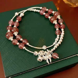 Dettaglio del bracciale in cristallo fragola con campanellino d'argento e fiocco