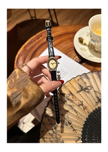 Detail of elegant gold oval watch with crystal bezel and black leather strap on a model hand