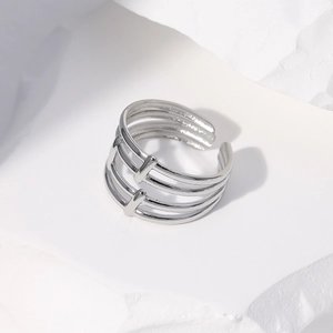 Detailed close-up of a silver multi-layer hollow open ring on a white textured stone surface