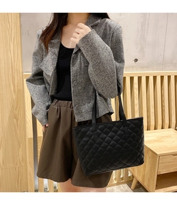 Classic black quilted tote bag with dual leather handles shown on a model
