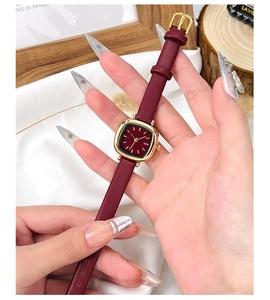 Gros plan d'une montre à quartz vintage bordeaux avec index dorés et bracelet en cuir