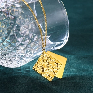 Detail of gold geometric square pendant with hammered texture on a clear glass rim