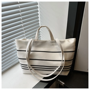 Macro shot of striped canvas tote bag showing the texture, double handles, and shoulder strap