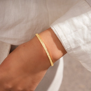 Detail of 18k gold plated bangle featuring elegant ribbed texture and geometric metal finish