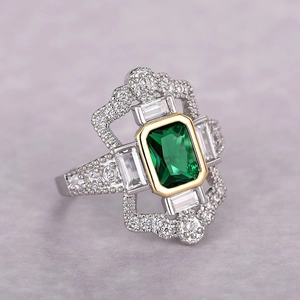 Anillo estilo art déco con esmeralda rectangular, acentos dorados y piedras brillantes