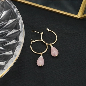 Detailed close-up of pink crystal drop earrings with golden rings and small pearl accents