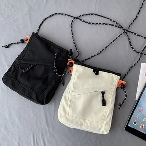 Detailed view of nylon utility crossbody bags in black and beige with orange strap details