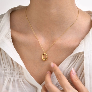 Minimalist brass necklace with irregular gold oval pendant worn on collarbone