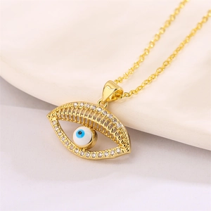 Detail of gold evil eye pendant with blue crystals on soft white fabric background