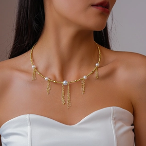 Close-up of gold fringe necklace with pearls worn on model, showcasing elegant tassel details