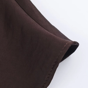 Detail shot of high-quality dark brown satin fabric with fine stitching and silky texture