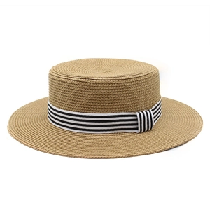 Detail of boater straw hat featuring woven texture and black and white striped ribbon