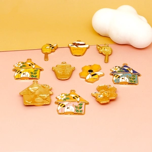 Macro view of colorful enamel bee and honey jar charms with golden edges on a pink background