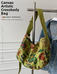 Close-up of green canvas messenger bag with vintage prints and wide shoulder strap