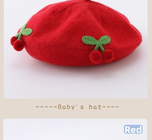 Close-up of red baby knit beret hat featuring handmade knitted cherry and leaf details