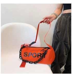 Détail du sac cylindre en nylon orange avec texte SPORT et grosse chaîne noire