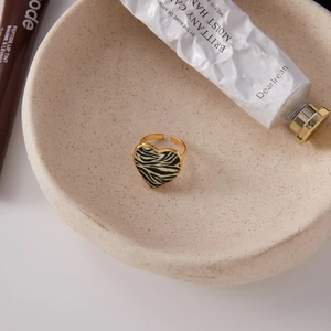 Detailed top view of gold heart open ring with zebra pattern in a minimalist setting
