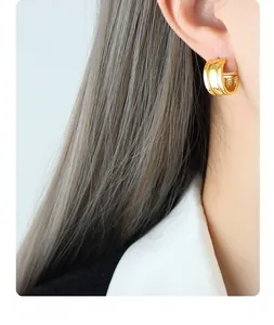 Close-up of triple-layered golden C-shaped hoop earrings worn on a female model