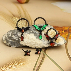 Macro shot of gothic bat body jewelry with red hearts and green enamel on stones