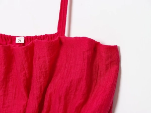 Détail de la texture plissée du tissu rouge et étiquette taille S sur l'ensemble jupe