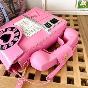 Close-up of pink vintage phone handbag with retro dial and receiver handle detail