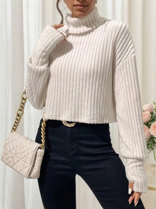 Elegante suéter blanco de cuello alto en punto acanalado para mujer con vaqueros negros