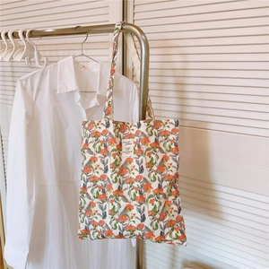 Detail der floralen Canvas-Tragetasche mit orangefarbenem Muster und Textiletikett
