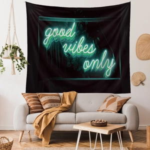 Detail of neon green Good Vibes Only tapestry hung over a modern sofa in a cozy room