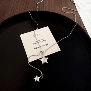 Detail view of silver star pendant necklace with layered charms on a black display surface