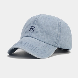 Detailed view of the dark blue embroidered letter R on a light blue denim baseball cap