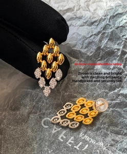 Vue macro des boucles d'oreilles losanges avec zircons sertis et accents dorés