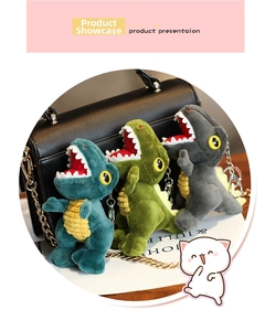 Three plush dinosaur keychains in blue, green, and grey on a black leather bag