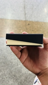 Close-up of a two-tone black and cream rectangular jewelry box held to show the side profile