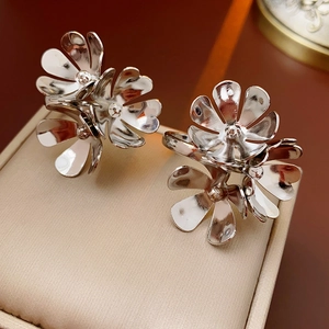 Detail shot of silver flower earrings with layered petals on a beige jewelry cushion