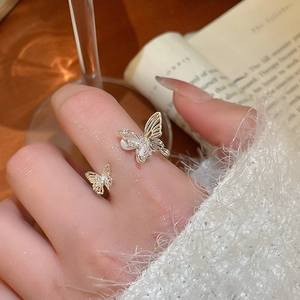 Close-up of elegant gold butterfly ring with white shell wings and zircon on hand