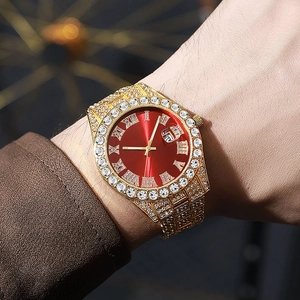 Close-up of luxury gold iced out watch with red dial and roman numerals on wrist