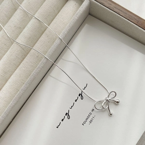 Detailed close-up of a S925 sterling silver bow pendant on a delicate snake bone chain