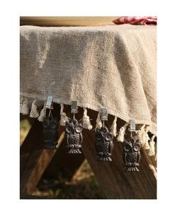 Détail de quatre poids de nappe chouette en fonte avec pinces en acier sur du lin