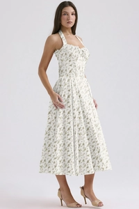 Close-up of green floral print pattern and lace detail on white halter neck dress