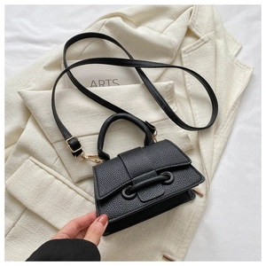 Detail of black lychee texture leather handbag featuring a unique double knot buckle design