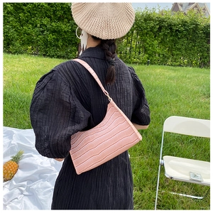 Pink crocodile pattern leather underarm bag shown in a sunny outdoor picnic setting
