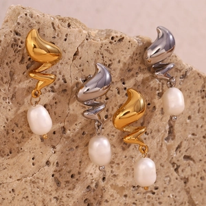 Macro shot of gold and silver baroque pearl earrings on a textured stone background