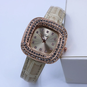 Detailed macro view of a rose gold square watch with crystal bezel and beige leather strap