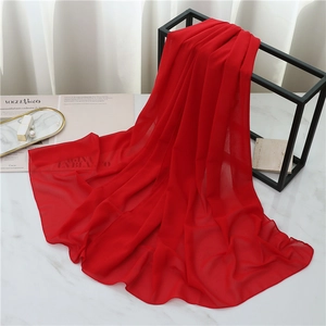 Detailed close-up of a red chiffon scarf draped elegantly over a black metal stand
