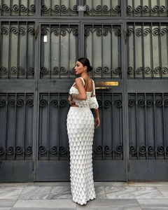Detail of white knit two-piece set featuring a scale texture skirt against a vintage gate