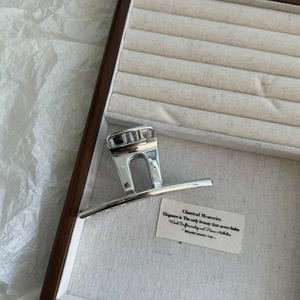 Close-up of a sleek silver geometric hair claw clip on a premium wooden display tray