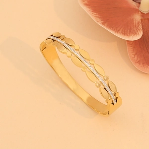 Macro view of gold metal bracelet with sparkling pavé crystals and wave link details