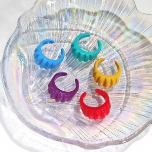 Detail of colorful acrylic open rings set with wavy texture in iridescent shell dish