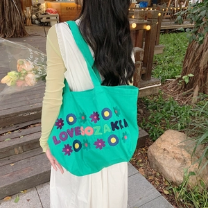 Green canvas tote bag with floral embroidery and long shoulder straps for daily use